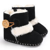 Black baby boots with white fur trim and wooden button on a white background