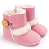 Pink baby boots with white fur trim and a wooden button on a white background
