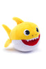 Plush toy shark with a yellow body, black eyes, and red mouth on a white background