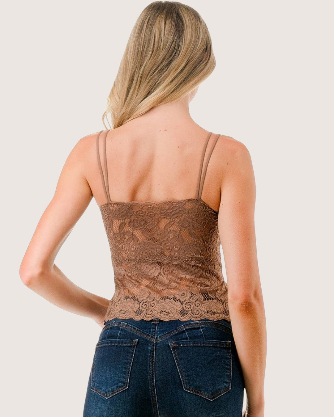 Woman wearing a brown lace tank top and blue jeans on a white background