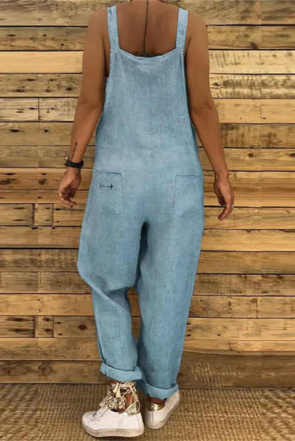 Person wearing a light blue denim overalls against a wooden wall.