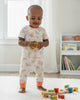 Child playing with toys on a rug in a room with books and a window.