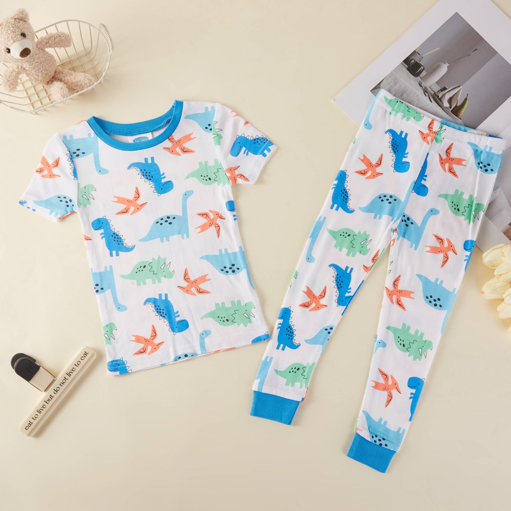 Children's pajama set with dinosaur pattern on a beige surface