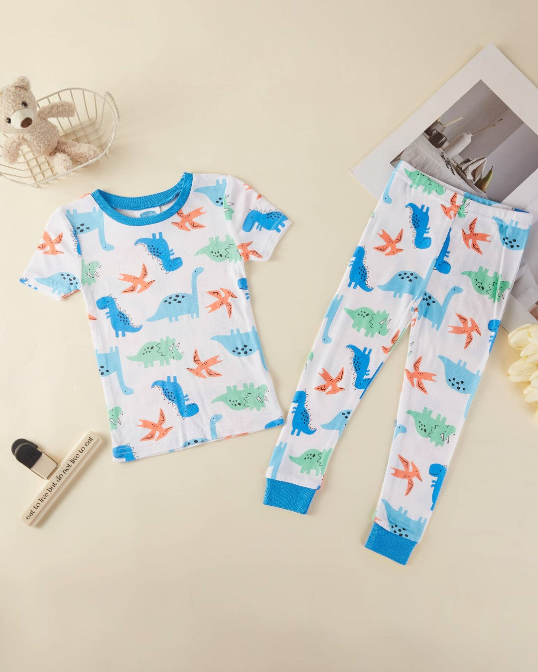Children's pajama set with dinosaur pattern on a beige surface