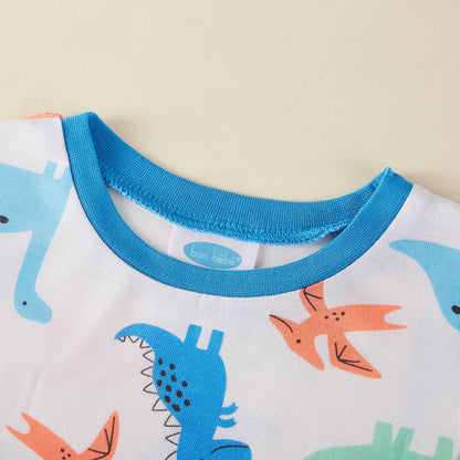 Children's pajama top with dinosaur pattern and blue collar on a beige background