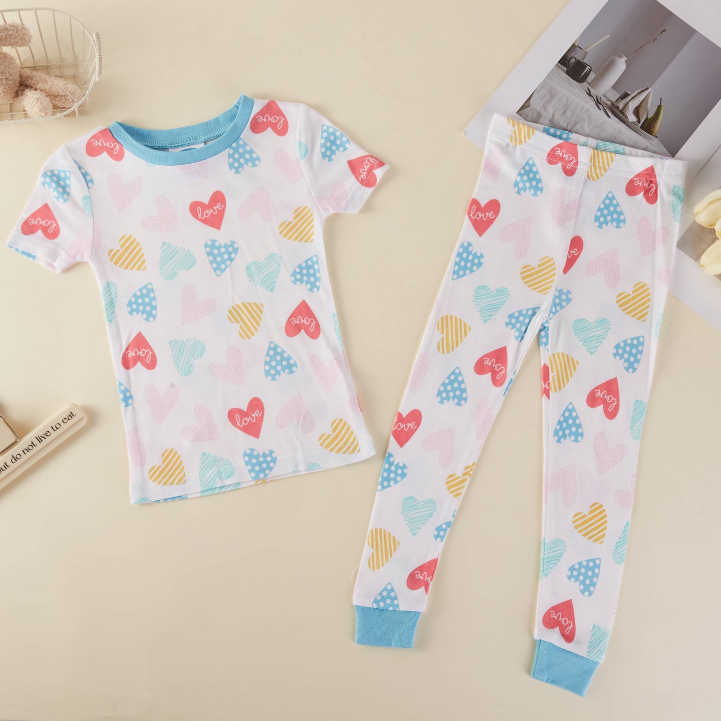 Children's pajama set with heart patterns on a beige surface