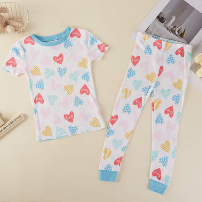 Children's pajama set with heart patterns on a beige surface