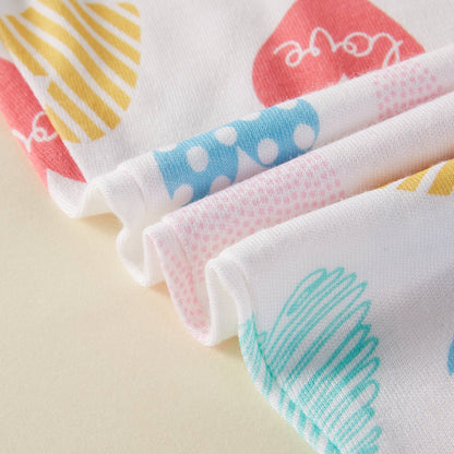 Set of colorful baby bibs with different patterns on a beige background