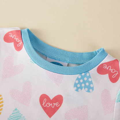 Close-up of a baby outfit with heart patterns and 'love' text on a light background