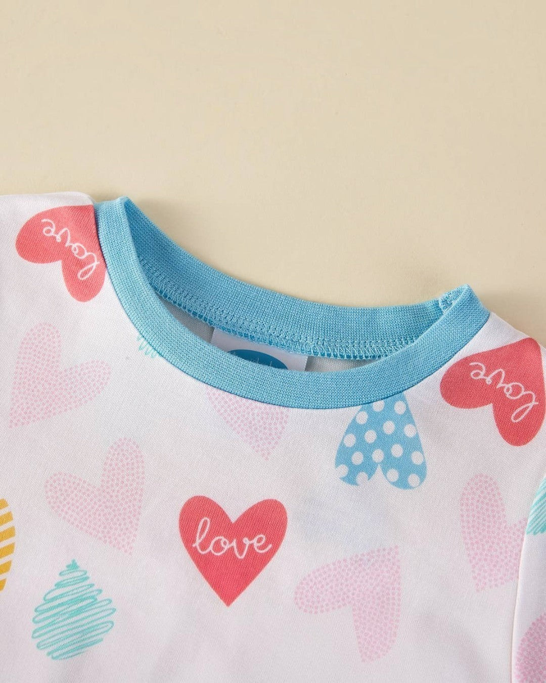 Close-up of a baby outfit with heart patterns and 'love' text on a light background