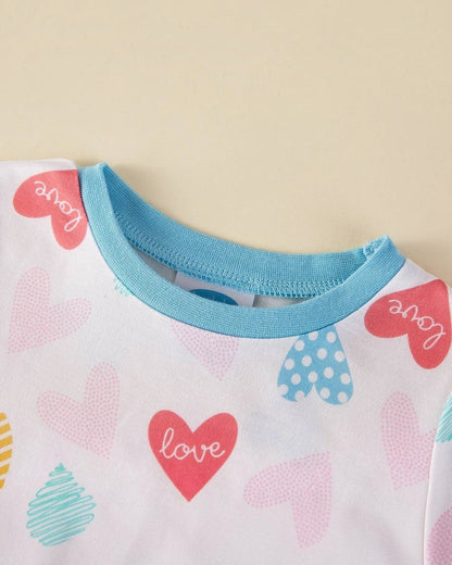 Close-up of a baby outfit with heart patterns and 'love' text on a light background