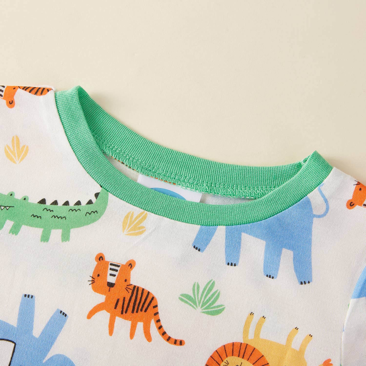 Close-up of a children's garment with green neckline and animal print design.