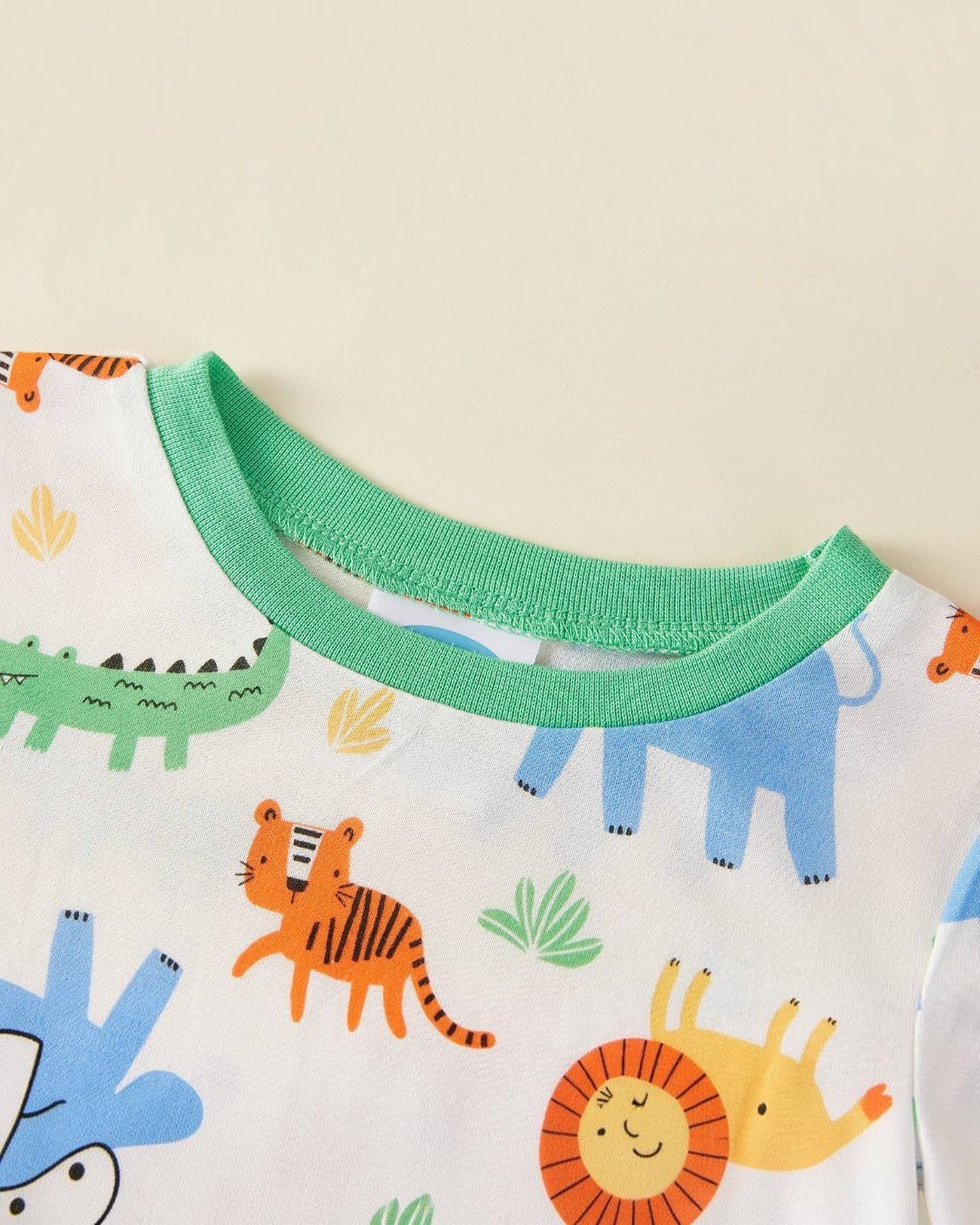 Close-up of a children's garment with green neckline and animal print design.