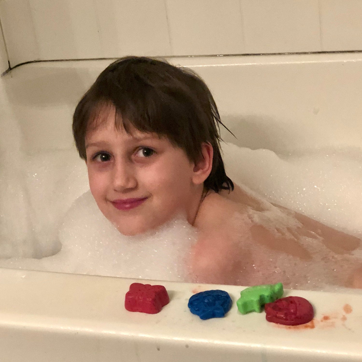 Child in a bubble bath with colorful bath toys