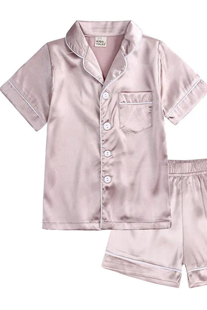 Pink satin pajama set with shirt and shorts on a white background