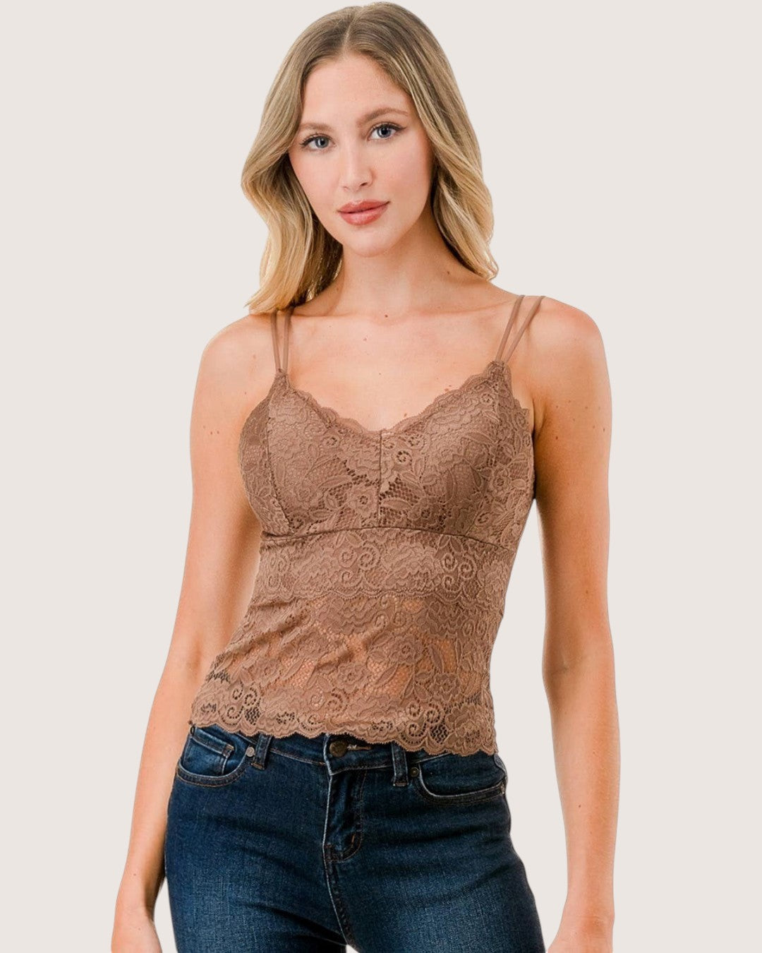Woman wearing a brown lace camisole and blue jeans on a white background