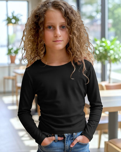 Young girl wearing a black long-sleeve shirt and blue jeans indoors.