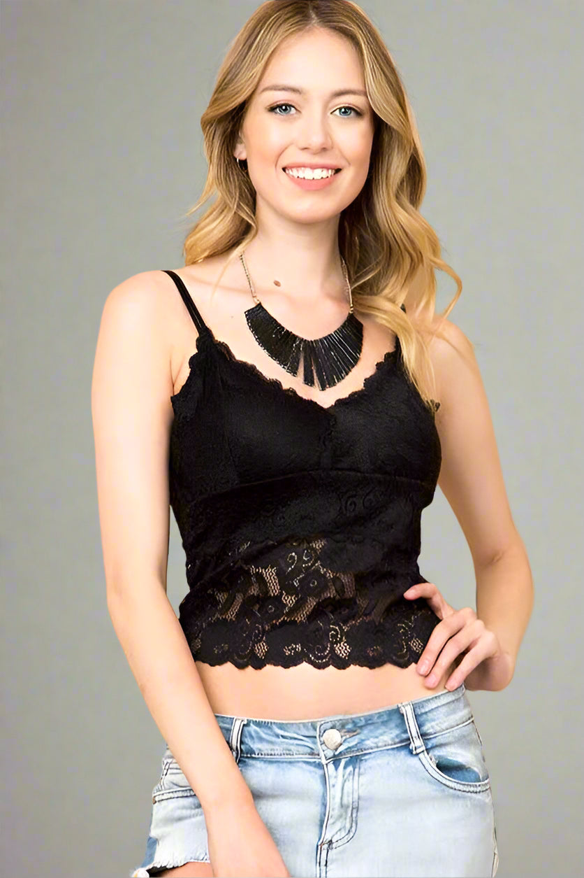 Woman wearing a black lace top and light blue jeans against a beige background