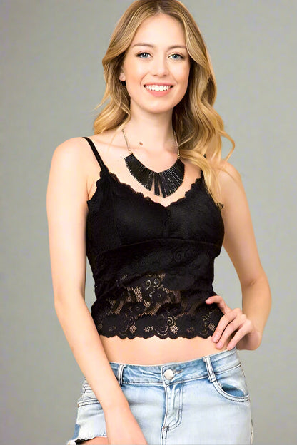 Woman wearing a black lace top and light blue jeans against a beige background
