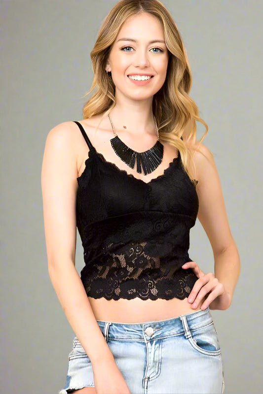 Woman wearing a black lace top and light blue jeans against a beige background