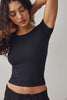 Woman wearing a black ribbed crop top against a plain background