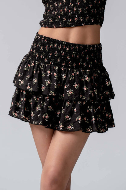 Black floral skirt with ruffled layers on a gray background