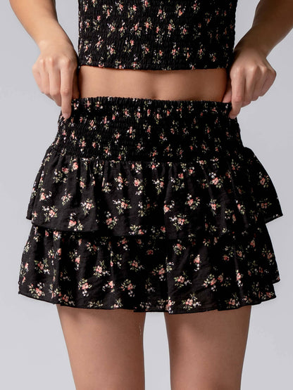 Black floral tiered skirt worn by a person on a gray background