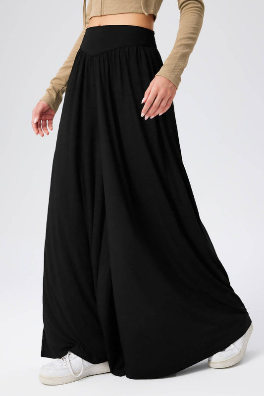 Person wearing a long black skirt with a plain background