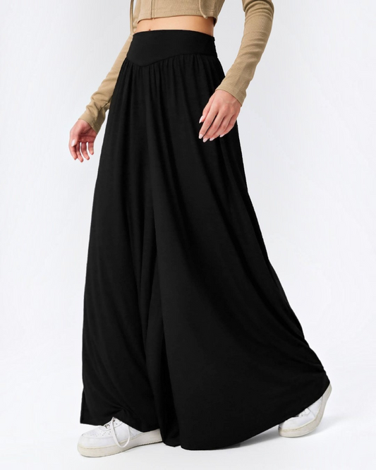 Person wearing a long black skirt with a plain background