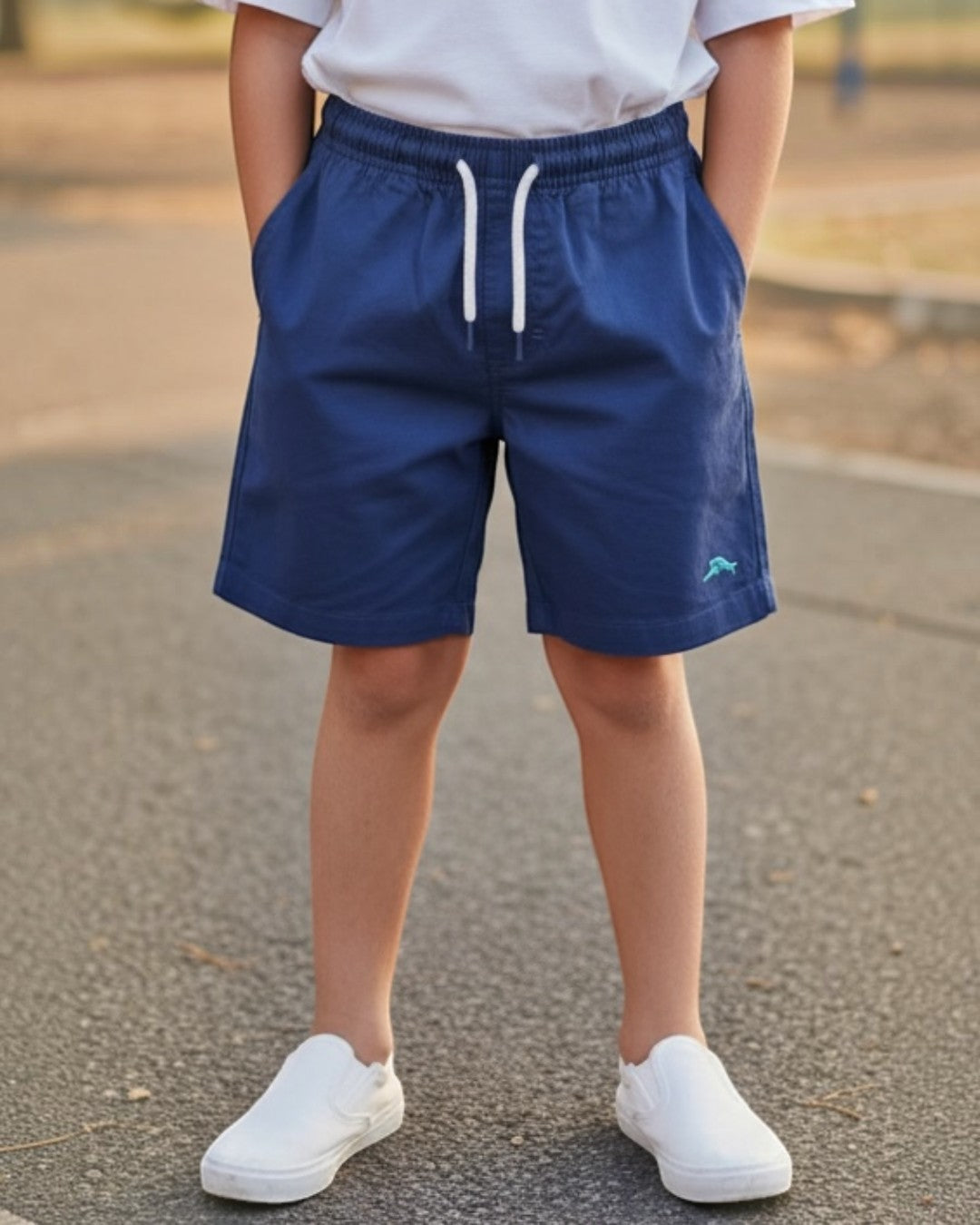 Young boy standing on a playground with a swing set in the background