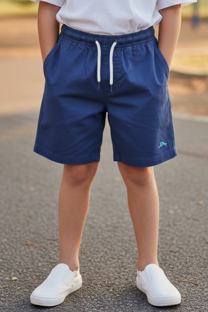 Young boy standing on a playground with a swing set in the background