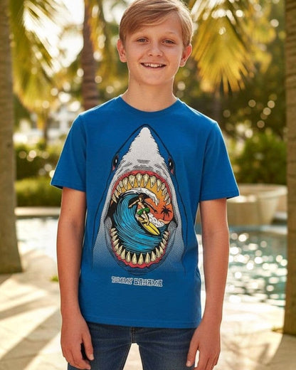 Child wearing a blue t-shirt with a shark graphic design, standing by a pool with palm trees in the background.