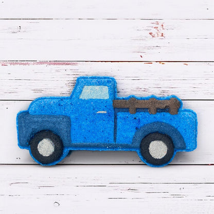 Blue bath bomb truck with a white bed on a wooden surface