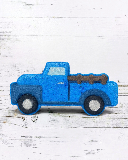 Blue bath bomb truck with a white bed on a wooden surface