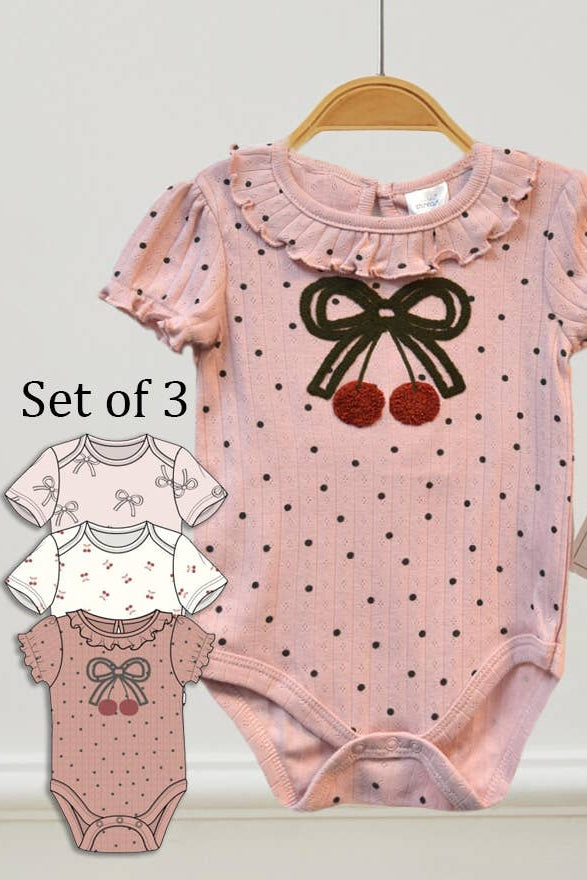 Set of three baby rompers with polka dot design and bow details on a white background.