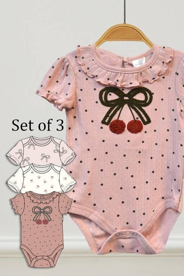 Set of three baby rompers with polka dot design and bow details on a white background.
