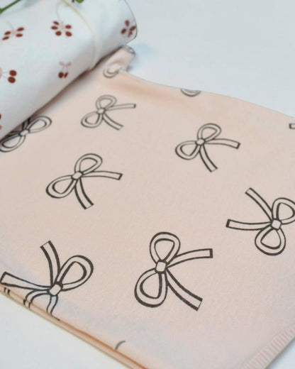 Fabric with black bow pattern on a light pink background