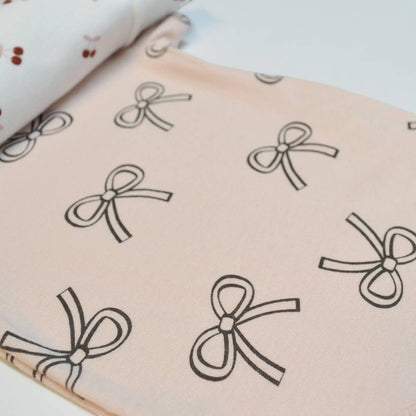 Fabric with black bow pattern on a light pink background