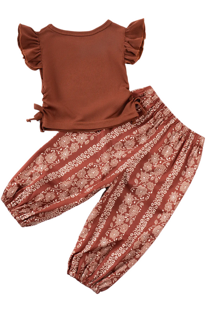 Brown top and floral pants set on a white background with yellow flowers.