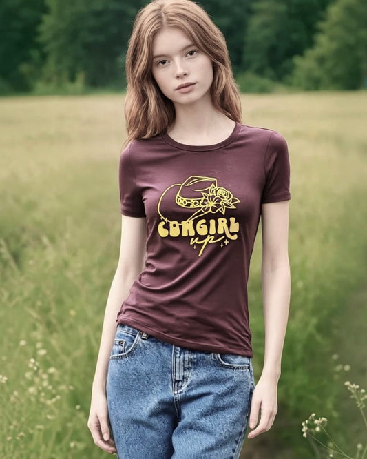 Person wearing a brown t-shirt with yellow text and graphics in a field