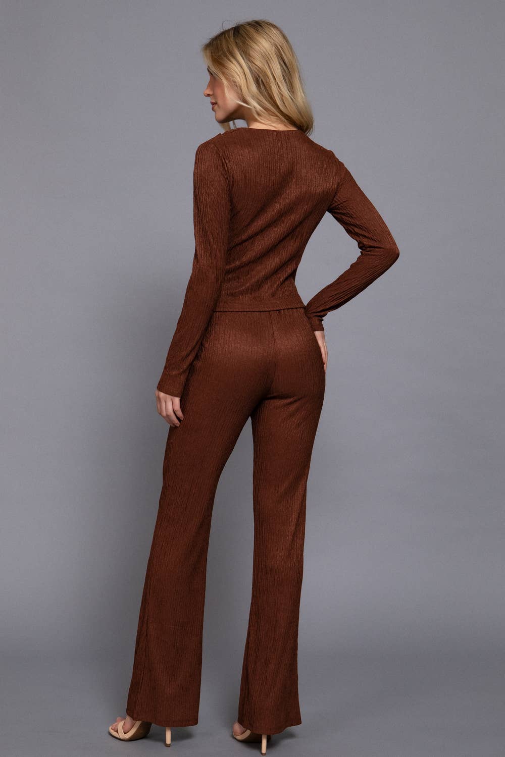 Woman wearing a brown jumpsuit against a gray background