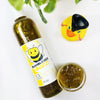 Bumblebee Buzz Shimmering Body Wash in a transparent bottle and cup of our golden yellow bumblebee buzz body wash against a white background
