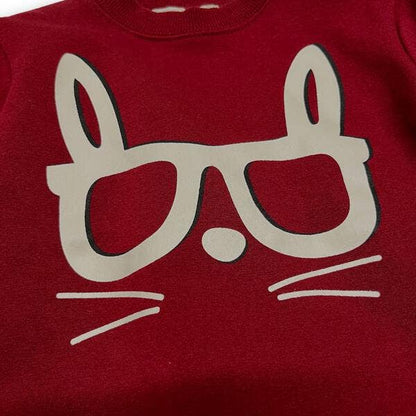 Red shirt with a beige cat face design on a plain background