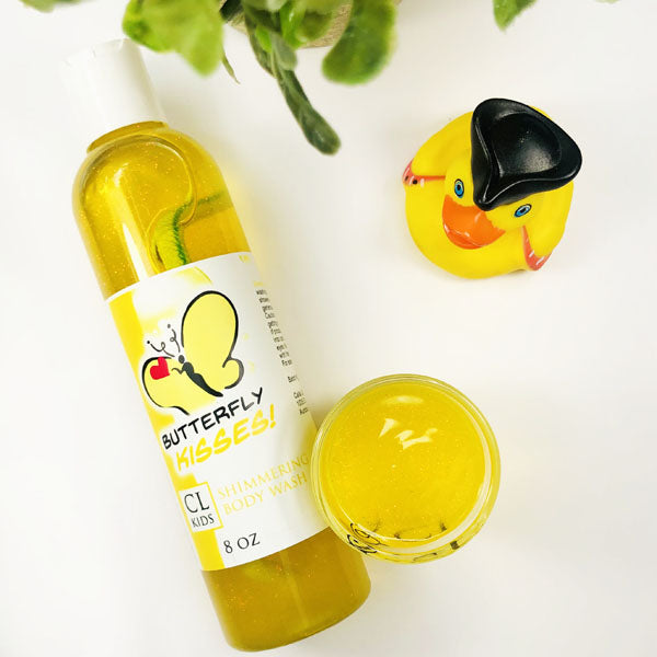 Butterfly Kisses Shimmering Body Wash in a transparent bottle and cup of our yellow butterfly kissses body wash against a white background