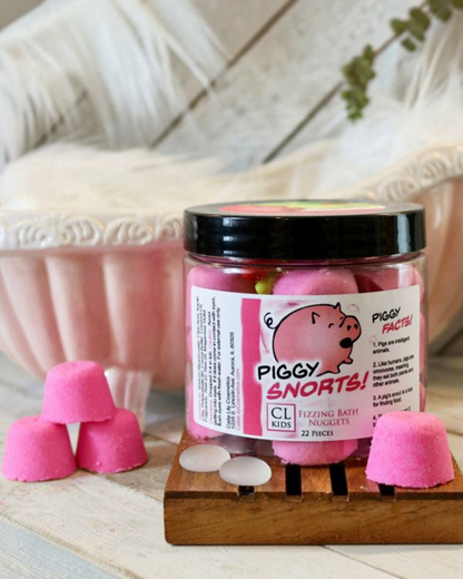 A container of gumdrop shaped pink "piggy snorts" bath bombs with a tiny 3 bath bomb pyramid to its side
