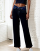 Person wearing dark blue jeans standing indoors with a light-colored wall background