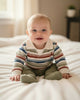 Children's outfit with striped shirt and green pants on a white surface