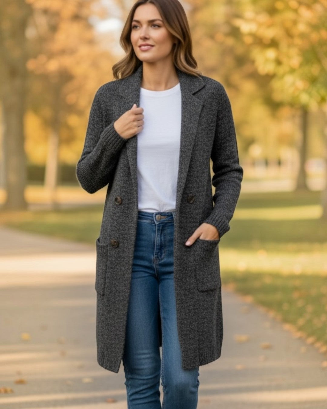 Woman wearing a gray coat, white shirt, and blue jeans outdoors.