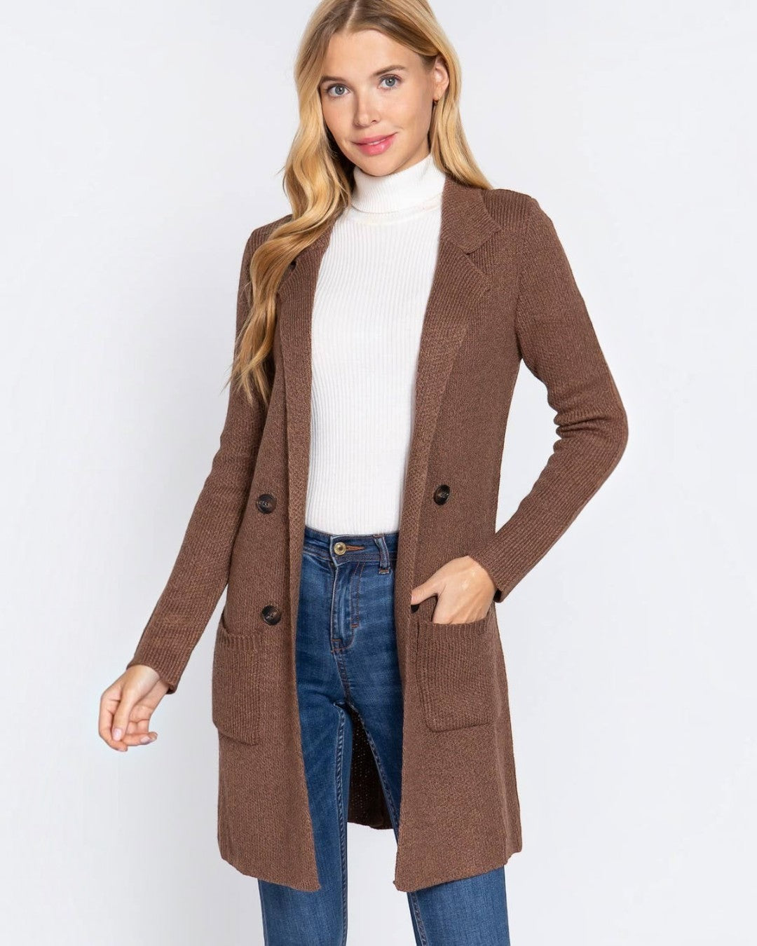 Woman wearing a brown coat over a white shirt and blue jeans on a white background