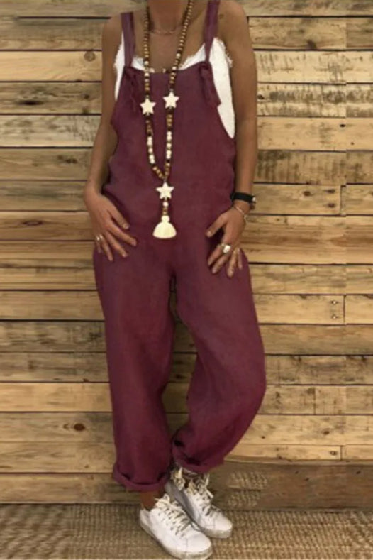 Person wearing maroon overalls with a wooden wall background